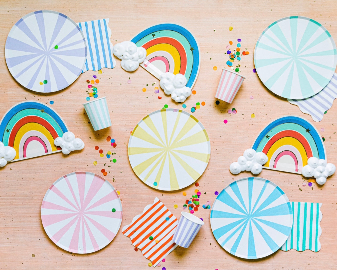 Rainbow stripe party supplies and rainbow plates set out for a birthday party.