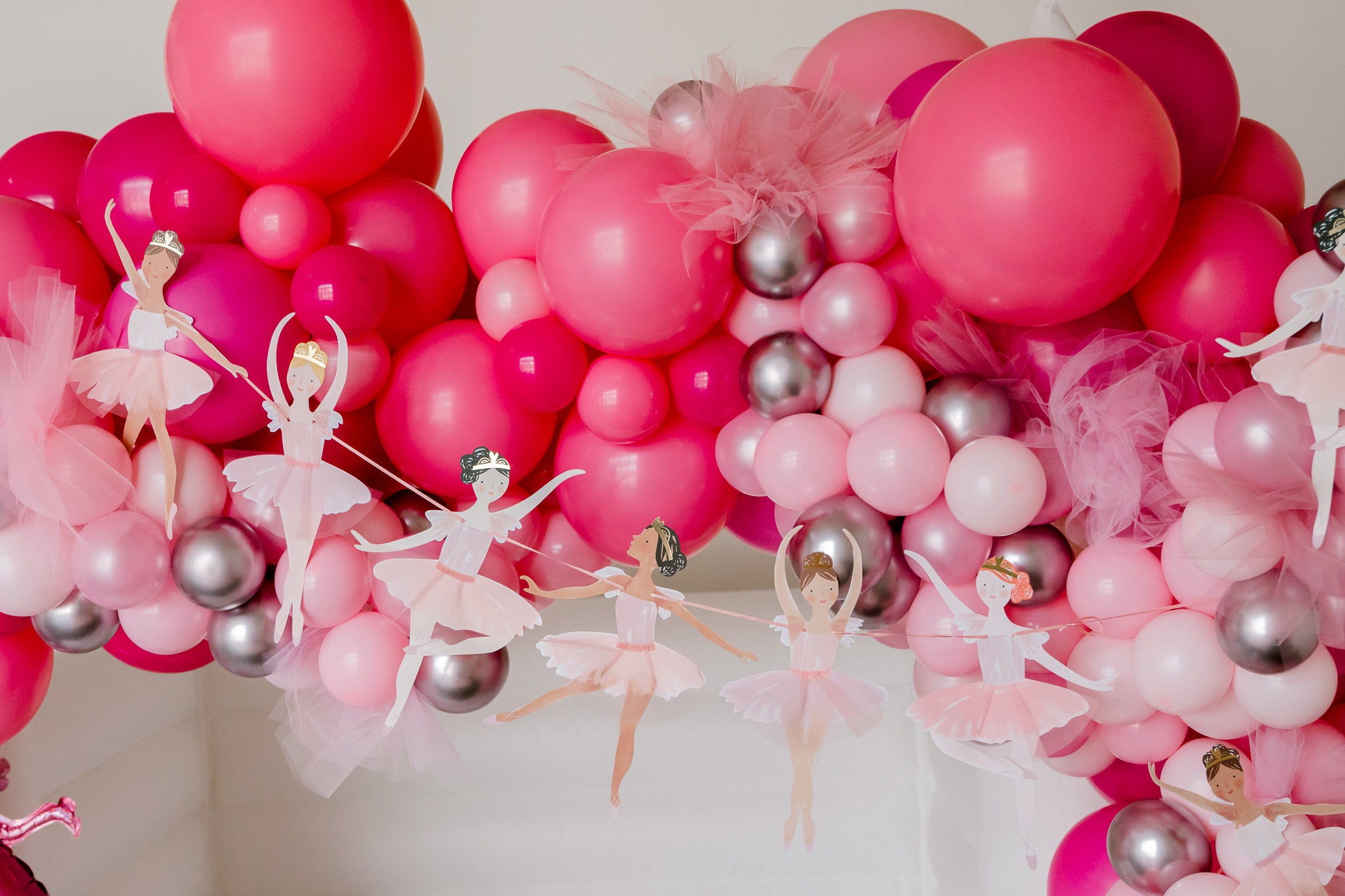 Ballerina birthday garland set up with a pink balloon garland for a ballet-themed birthday party.