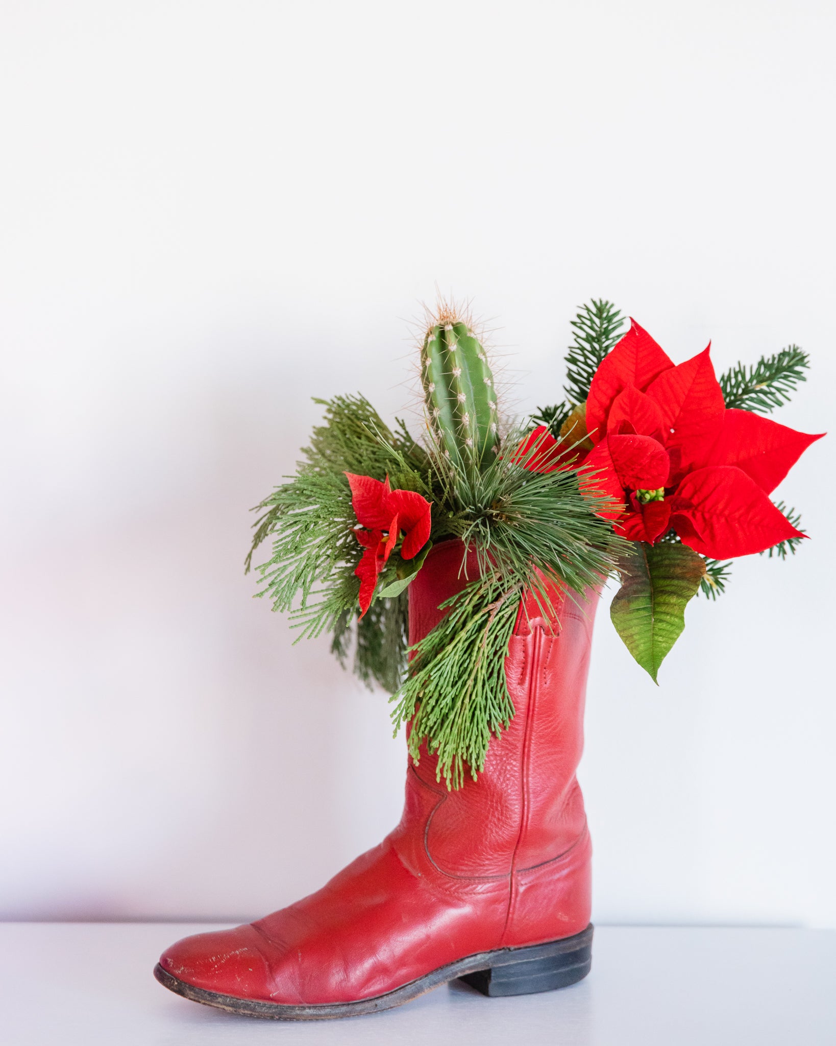 Cowboy boot used as a vase for a floral Christmas centerpiece.