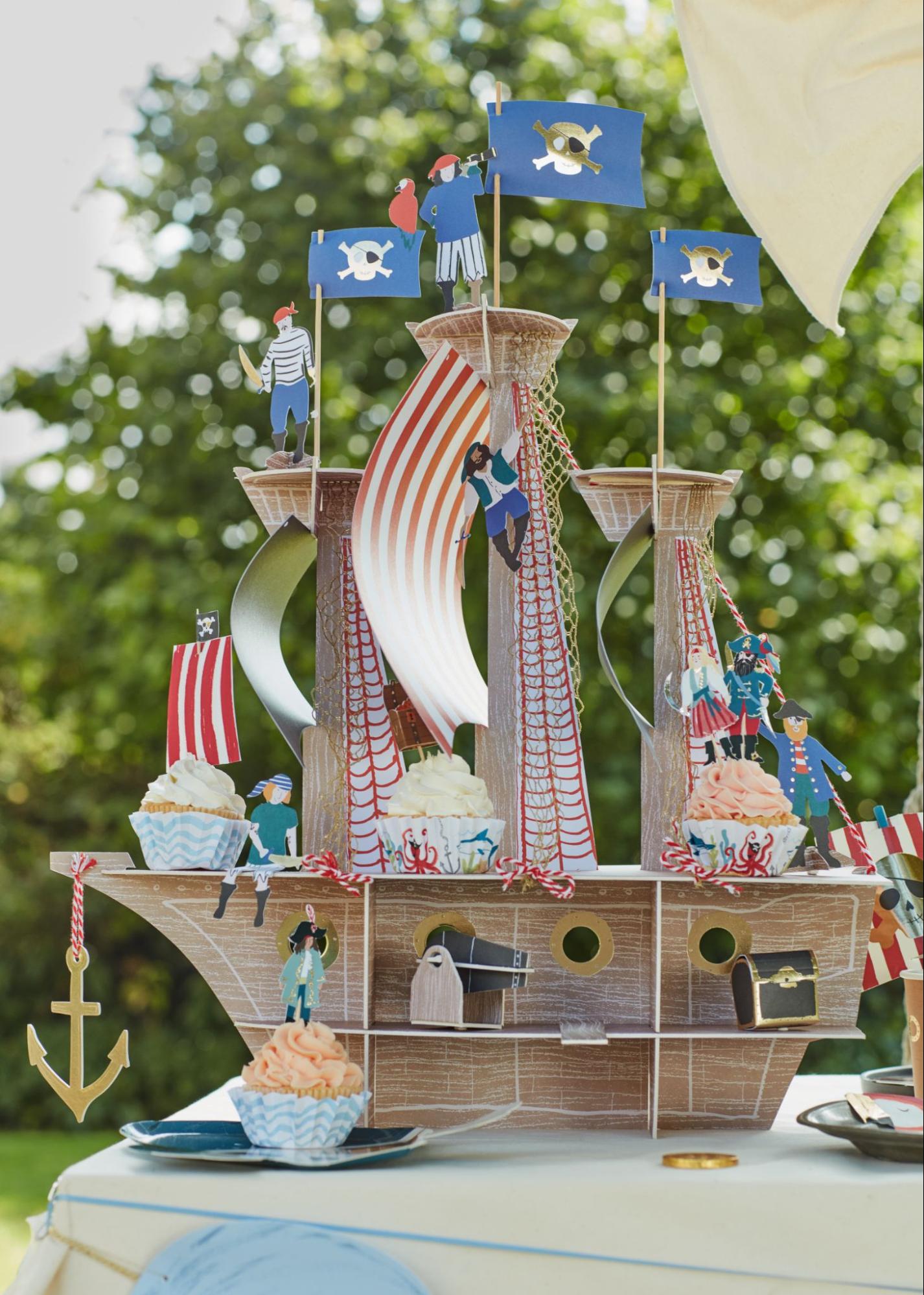 Pirate ship decoration with pirate birthday party cupcakes and pirate-themed toppers.