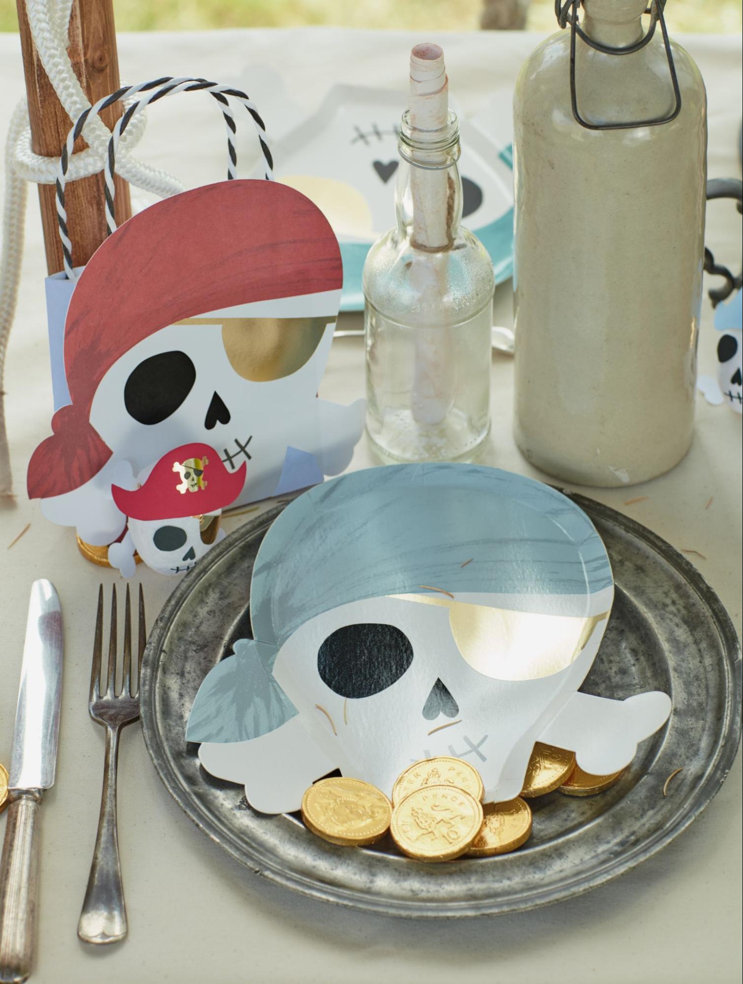 Skull and crossbones plates and other pirate-themed tableware set up at a pirate birthday party. 
