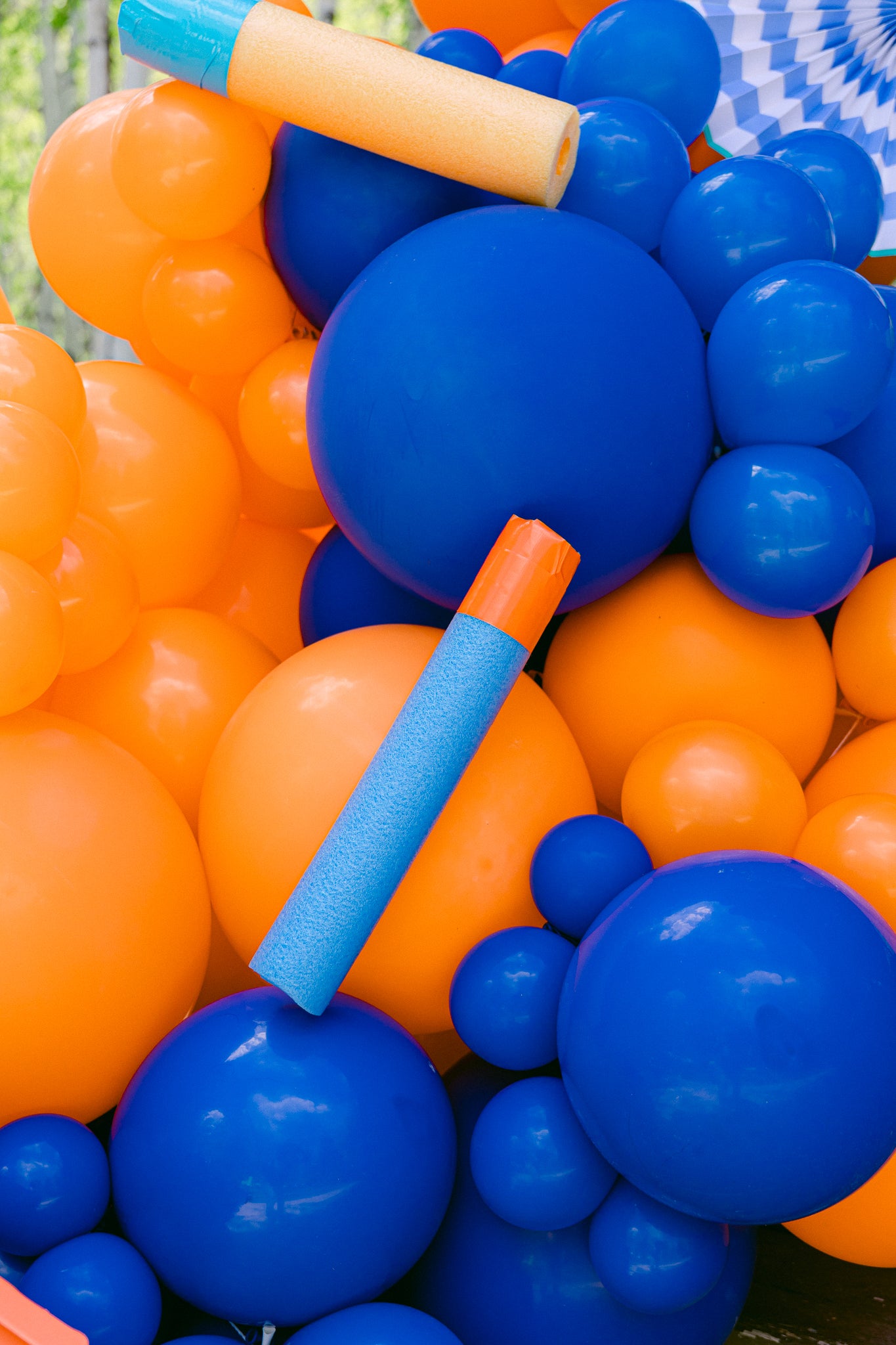 Nerf birthday party decorations using foam darts and orange and blue balloons.