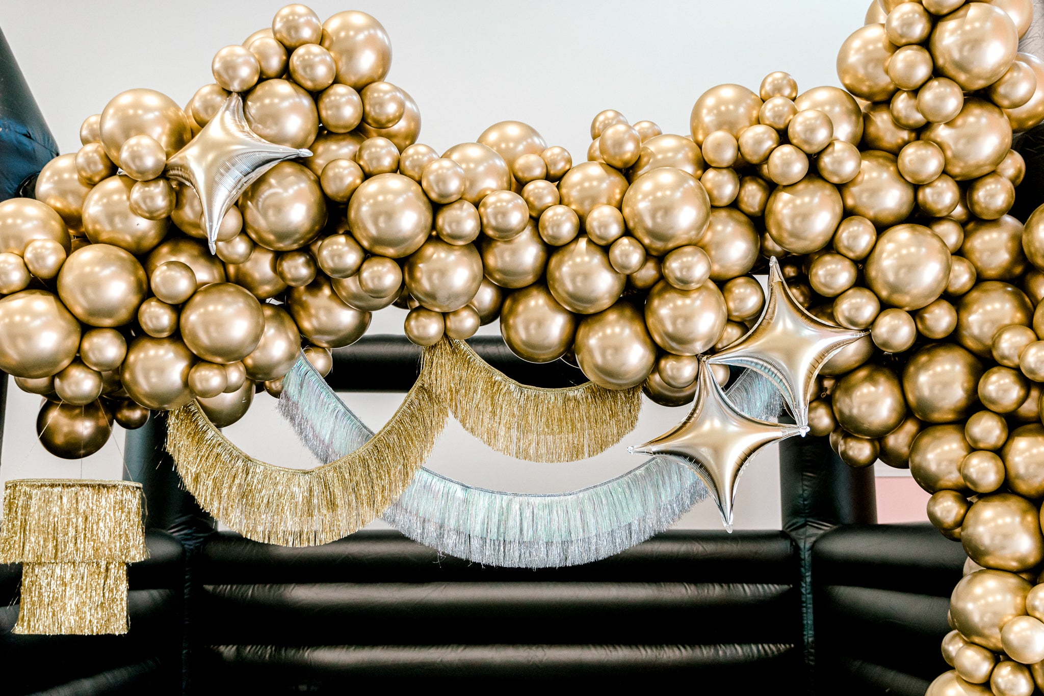 Silver and gold balloon garland on a bounce house for a fun New Years Eve party