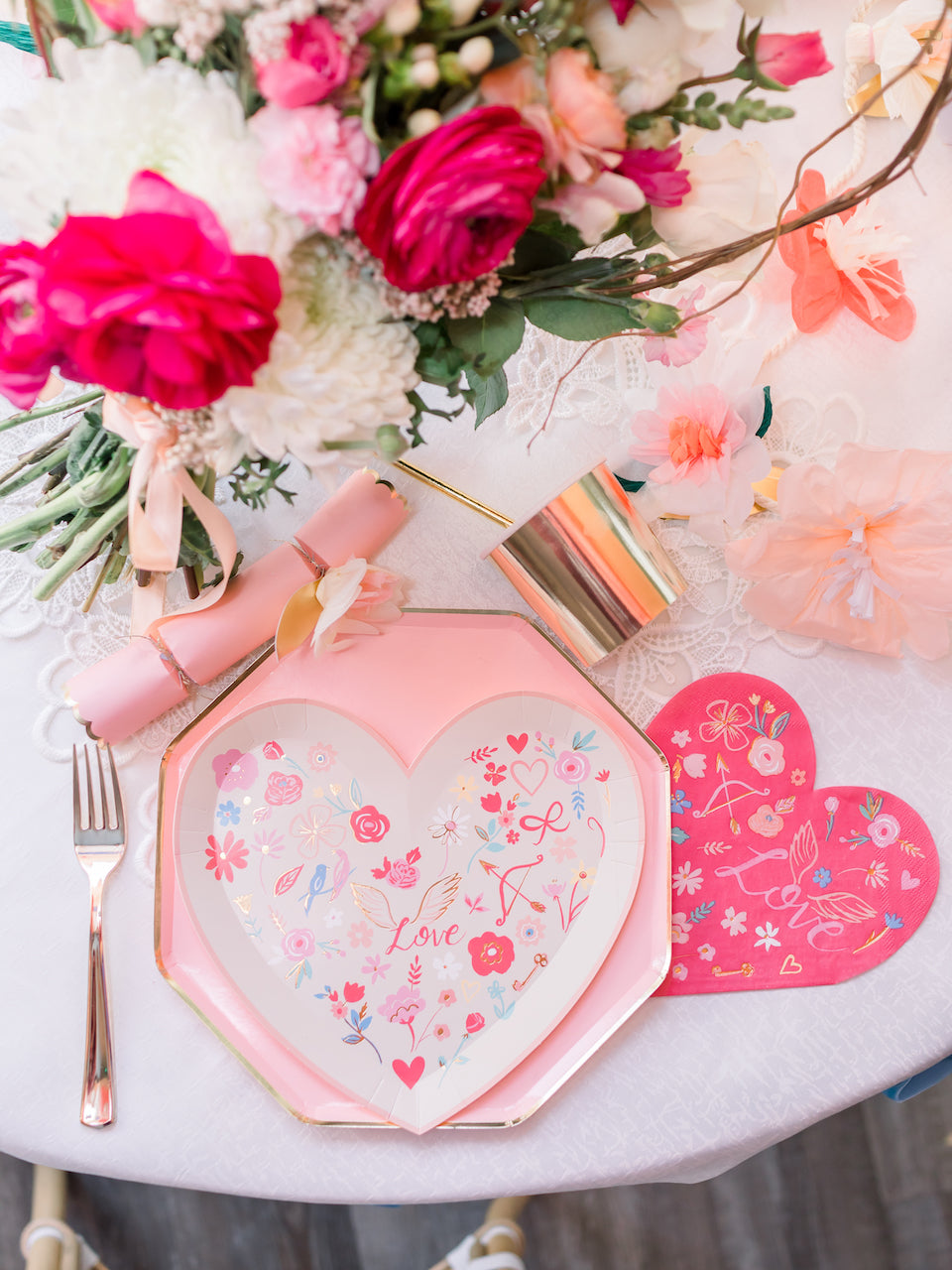 Heart shaped plates and pink party supplies set up at a Valentine's Day party