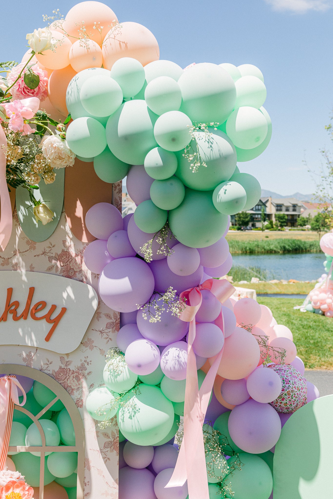 Pastel balloon garland decoration with flowers and bows for a girl's Paris-themed birthday party.