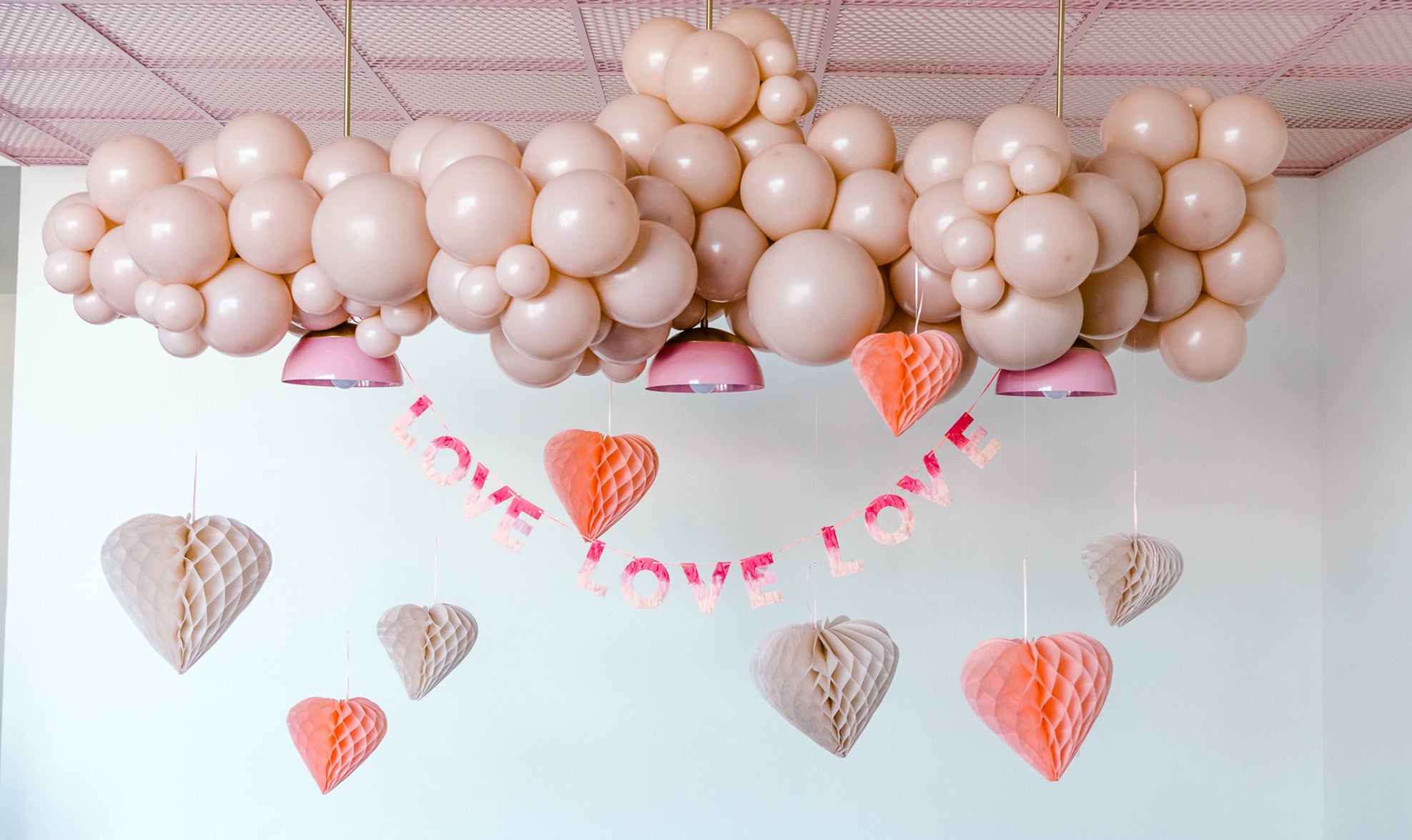 Honeycomb heart-shaped decorations with a balloon garland for Valentine's Day.