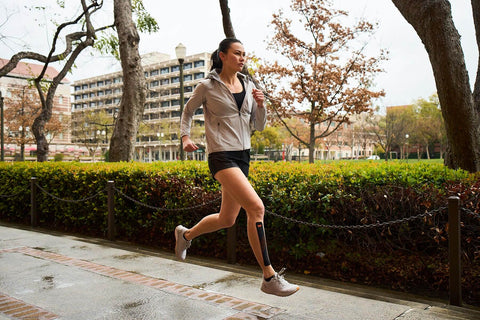 woman running with kinesiology tape for shin splints