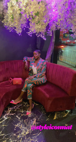 Natalie Robinson sitting in a London bar with the FLORE QUO pink Iris bag