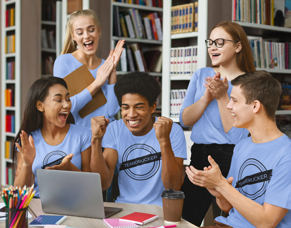Schüler in Abschlusskleidung von Teamdrucker schauen auf einen Laptop
