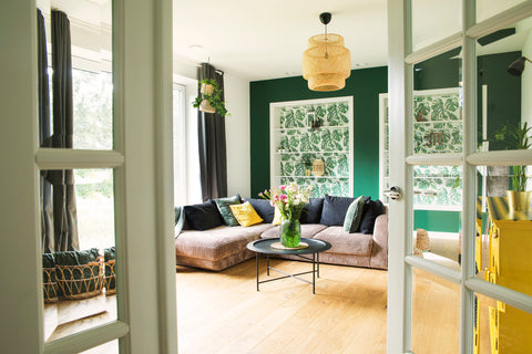 Living room with different colored walls, couch, wooden floor, and open windows