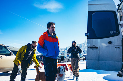 People and dogs in mountain parking lot. Blue skies.