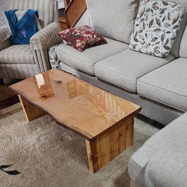 A wooden epoxy coffee table surrounded by light-grey fabric furniture.