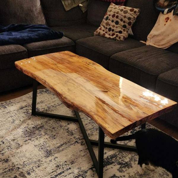 A sleek, live-edge wooden epoxy coffee table with metal table legs.