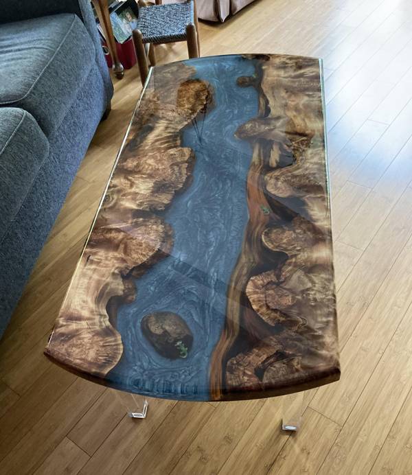 A wooden epoxy river table with a deep blue epoxy vein.