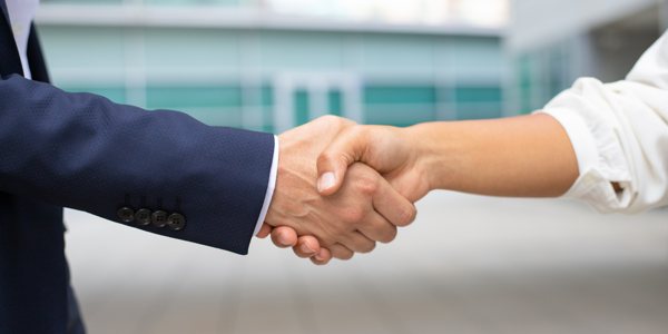 A close-up photo of two people performing a handshake.