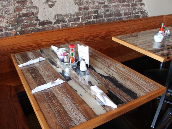 Multiple wooden epoxy table tops at a restaurant, set up for customers to eat at.