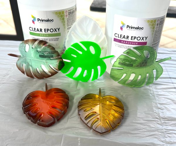Several epoxy resin coasters, each shaped like a leaf and colored with various Pigmently liquid pigments. They were made using Primaloc Epoxy Resin.