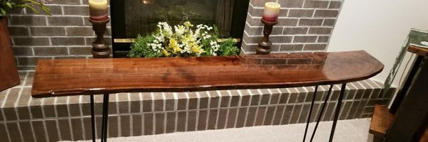 A wooden epoxy table top resting in front of an unlit fireplace.