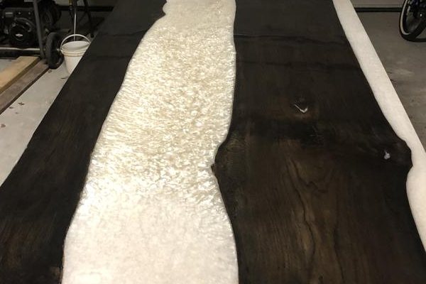 An epoxy river table with a white-tinted epoxy river vein and a topcoat of clear epoxy.