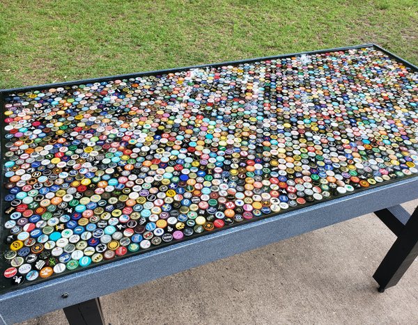 An epoxy bottlecap table top with a layer of embedded bottle caps.