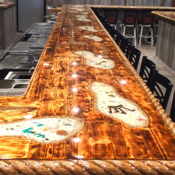 A seafloor-themed commercial wooden epoxy bar top with numerous embedments.