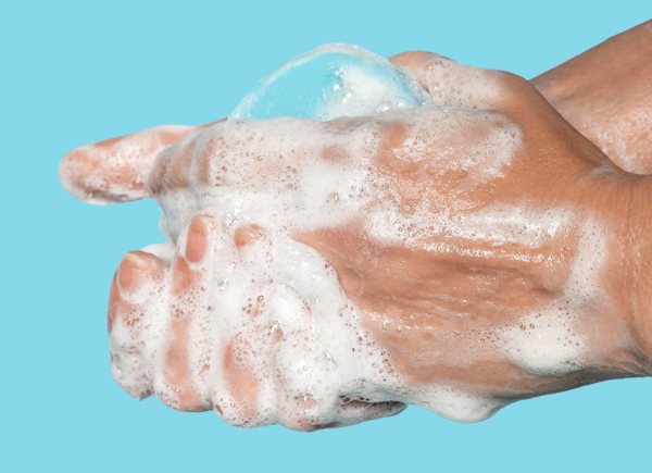 A closeup of a person's hands as they're being washed in sudsy water.