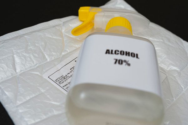 A spray bottle of 70% alcohol resting on a packing envelope.