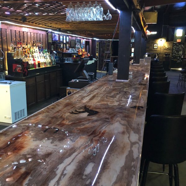 A very long indoor epoxy bar top at a commercial bar establishment.