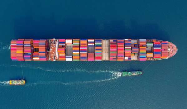 A freighter carrying numerous crates across the ocean.