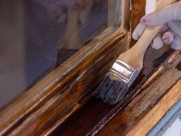 Varnish being applied to wood with a brush.