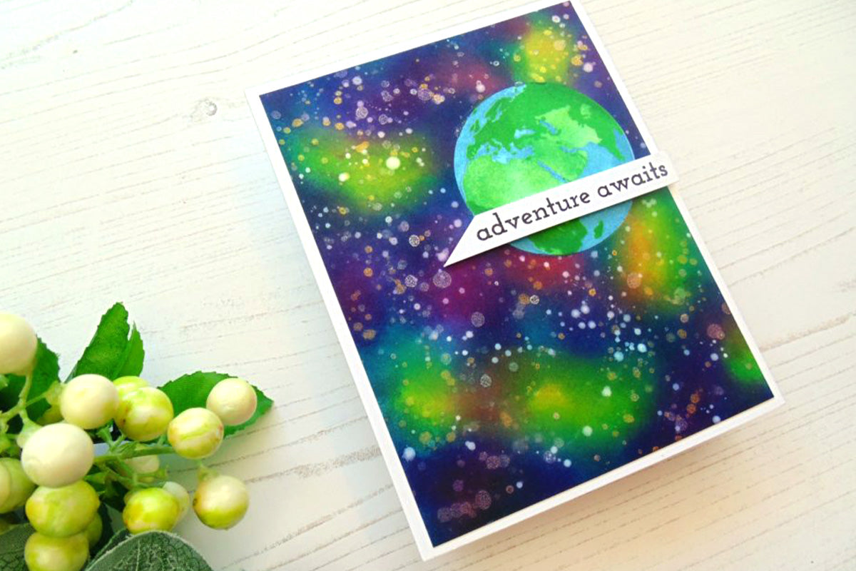 A card depicting a galaxy with the sentiment "adventure awaits", created through ink blending