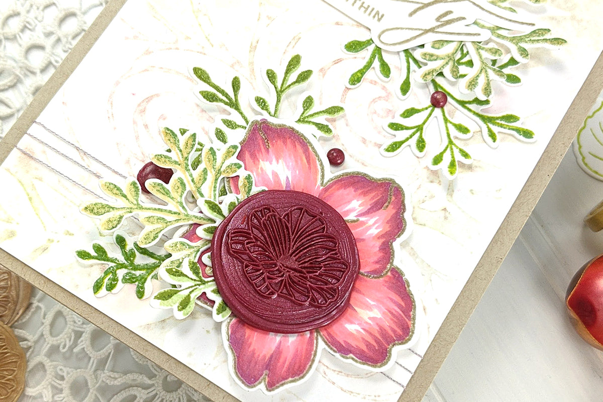 A close-up of a floral handmade card with a wax seal in the middle of the stamped flower