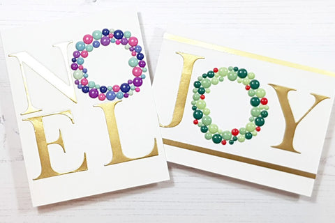 2 handmade holiday cards with O shaped enamel dots in different colors, spelling out the words Noel and Joy
