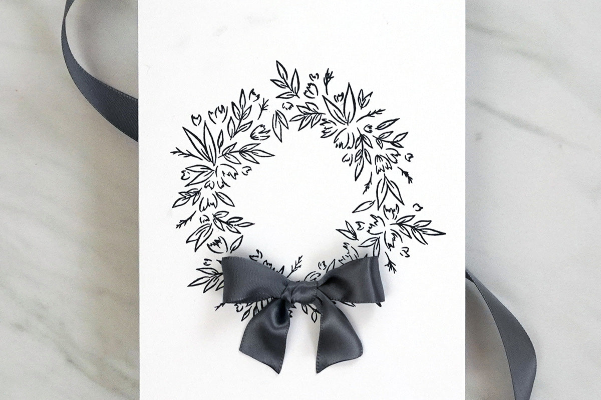 Minimalistic, masculine card with a black and white wreath design and a black bow
