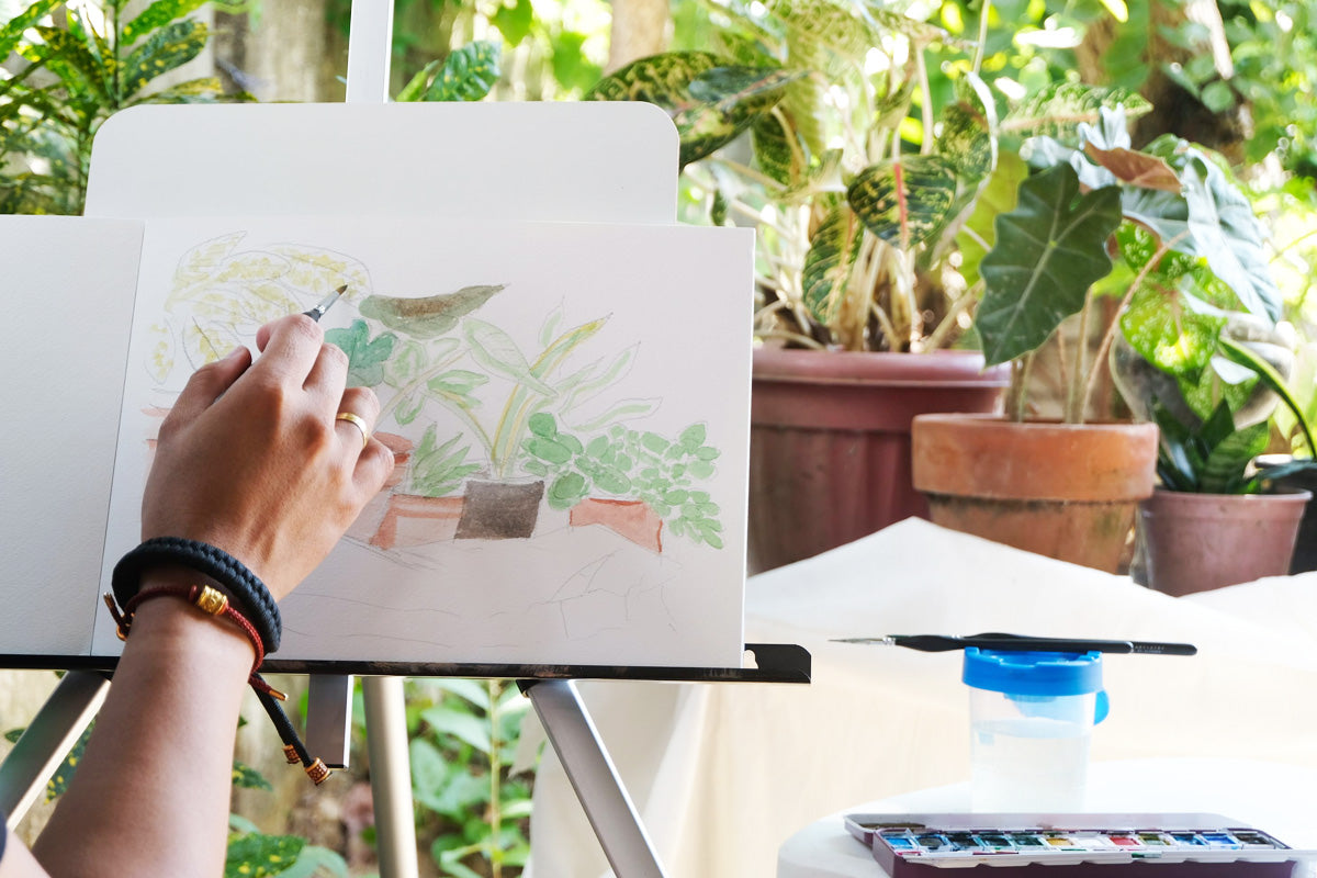 An artist painting some potted plants using Altenew's Artists' Watercolor Pan Set