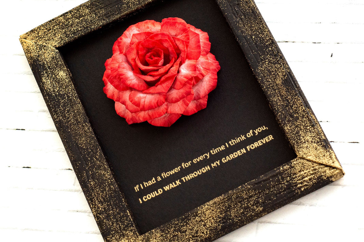 DIY wall decor on a black and gold frame with a red 3D paper flower