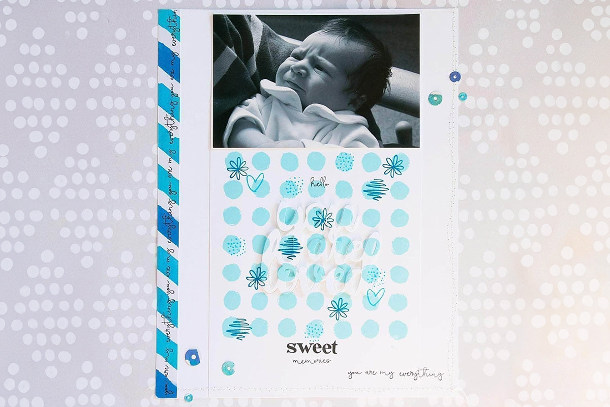 A scrapbook page entry about a little infant with a "hidden" die-cut message "You are loved", created with the hidden die cut technique