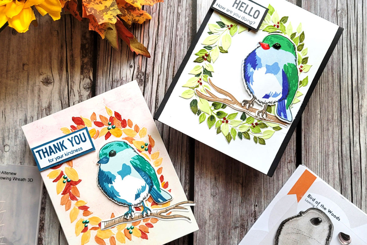 2 handmade cards with different colored leaf wreaths with a bird perched on them