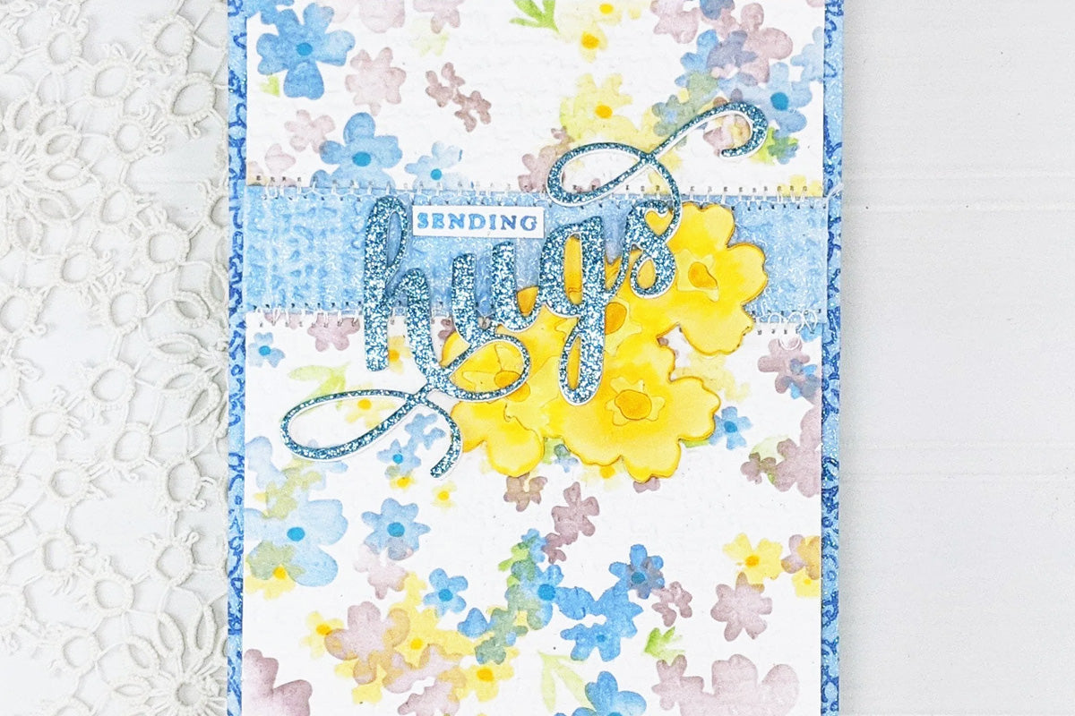 A "sending hugs" card with a lovely watercolored floral background and decorated with floral die-cuts, created with Altenew's pigment inks
