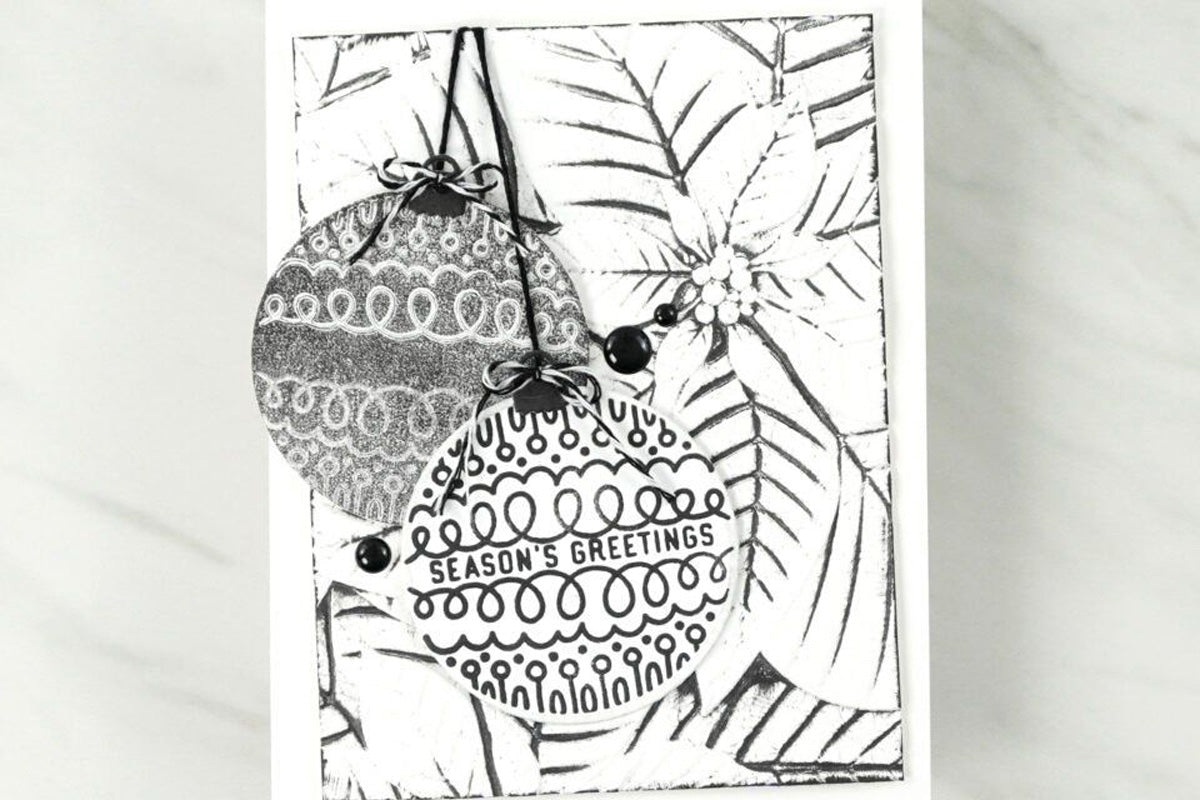 Black and white embossed poinsettia on an easy holiday card with black and white Christmas baubles
