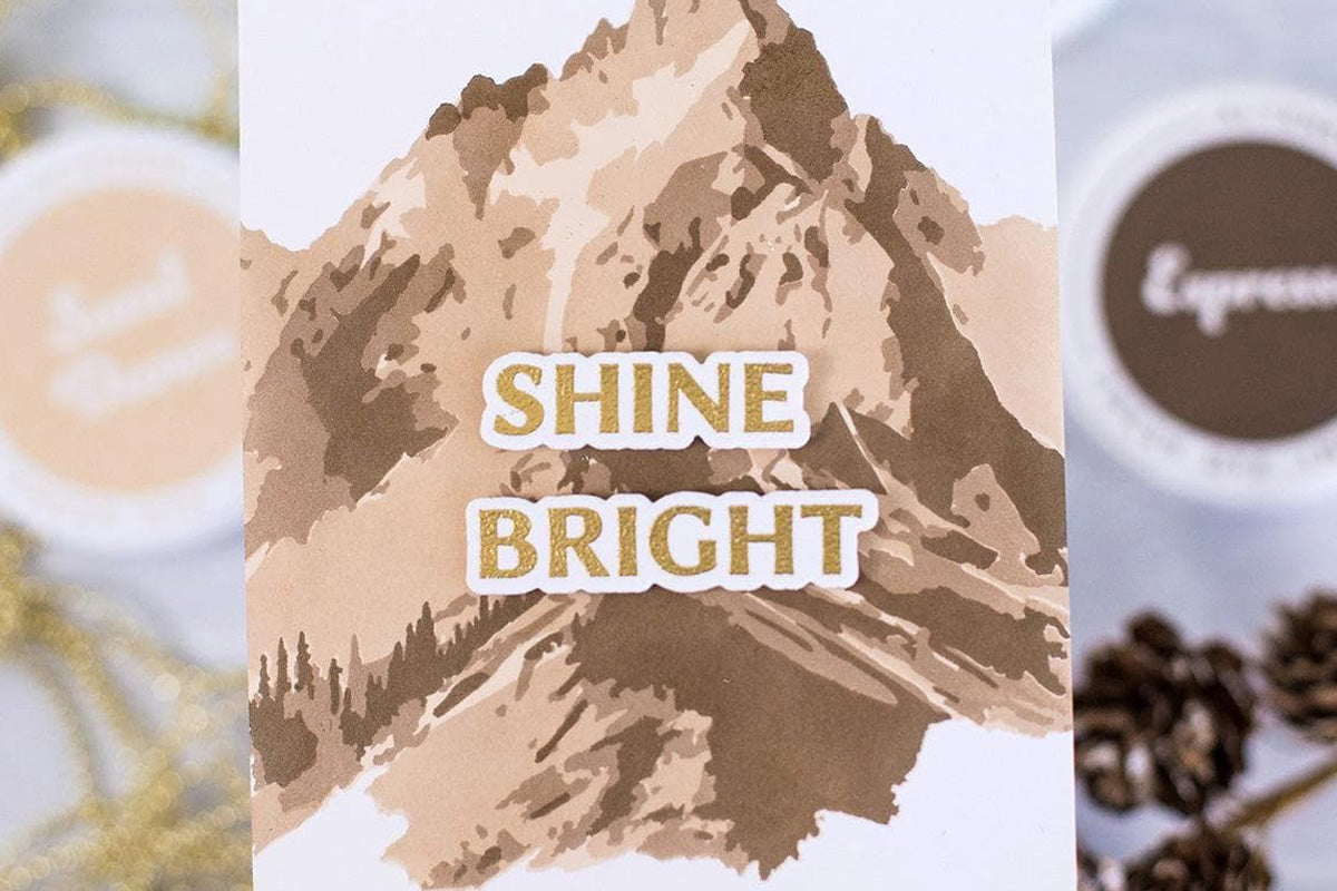 Monochrome card with a stenciled image of a mountain and the sentiment "shine bright"