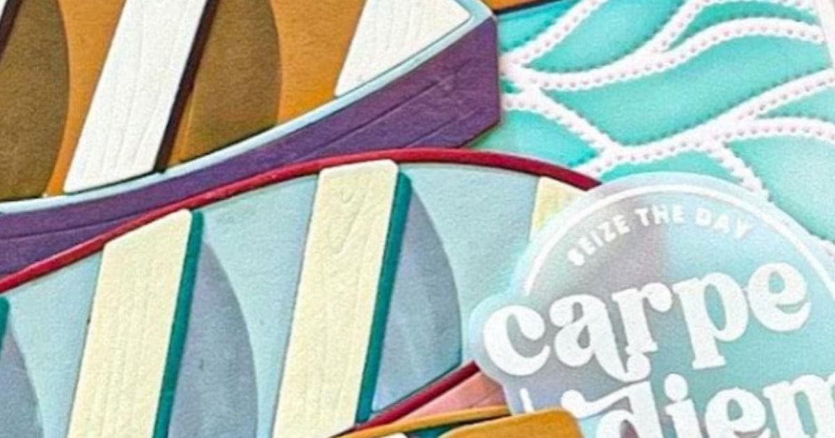 An image of a handmade card featuring a set of boats nestled together on a body of water alongside a 'carpe diem' sentiment