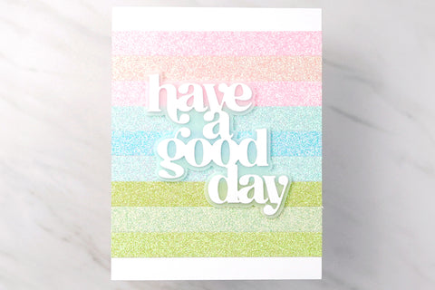 Cute rainbow card idea with different colored glitter cardstock strips in the background and the sentiment "have a good day"