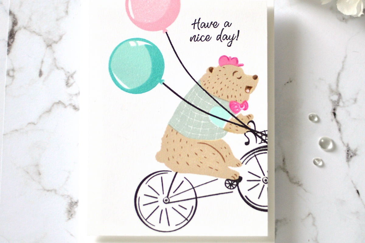 Cute Mother's Day card with a bear on a bicycle holding balloons