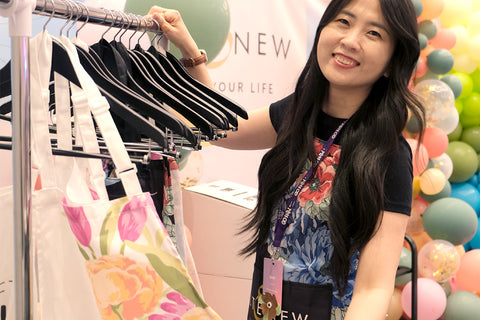 Altenew Marketing Director May Park showing off the new Artsy Aprons (hanging on a rack) at the Go Wild Conference 2024