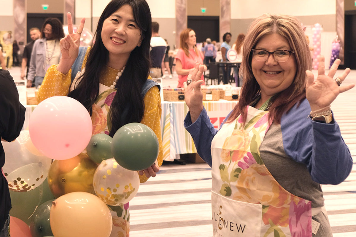 Altenew's marketing director May Park and a crafter wearing Altenew's Artsy Aprons at the Go Wild Planner Conference 2024