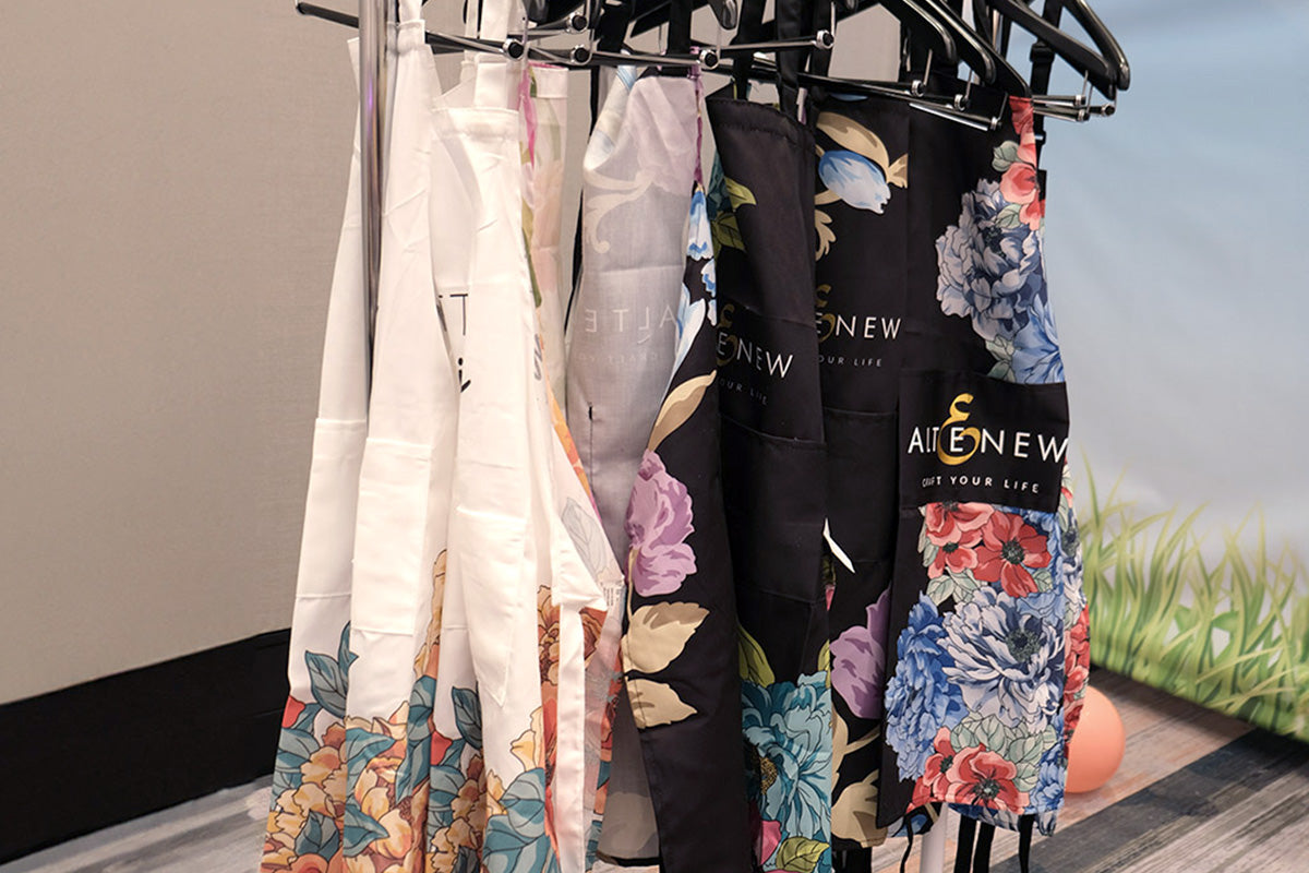 Altenew's Artsy Aprons hanging on a display rack at the Go Wild Planner Conference 2024