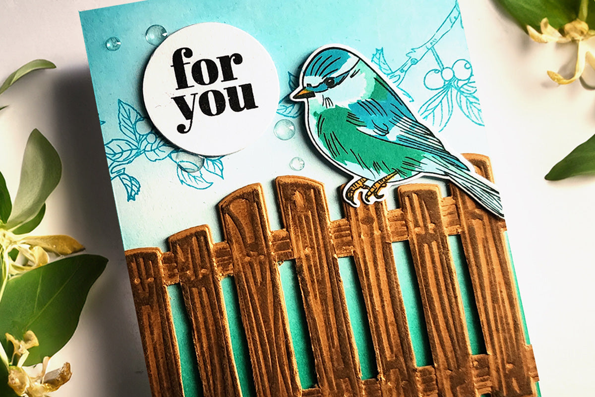 Handmade greeting card with a bird perched on a wooden fence, with 3D embossed and stamped details