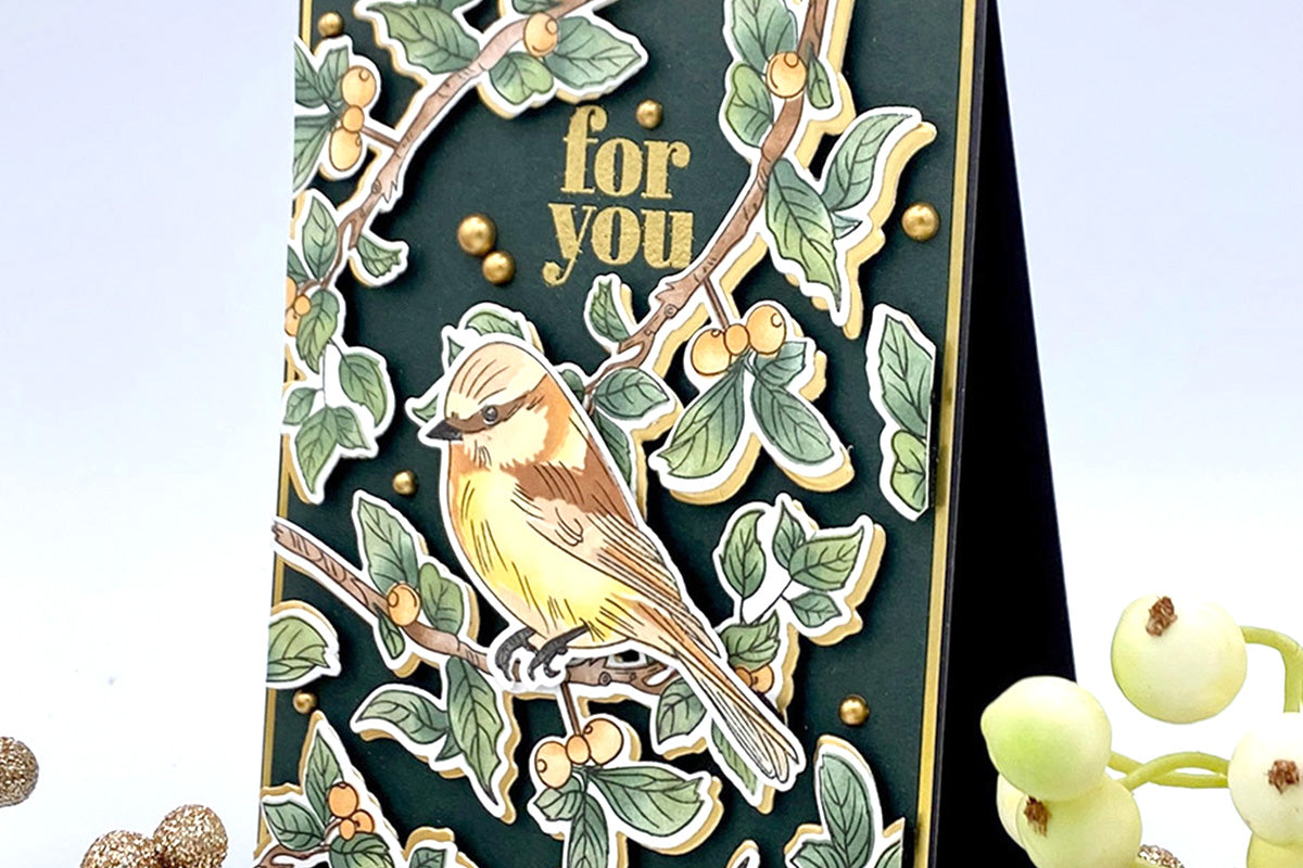 A green and gold greeting card with leafy branches in the background and a bird in the middle
