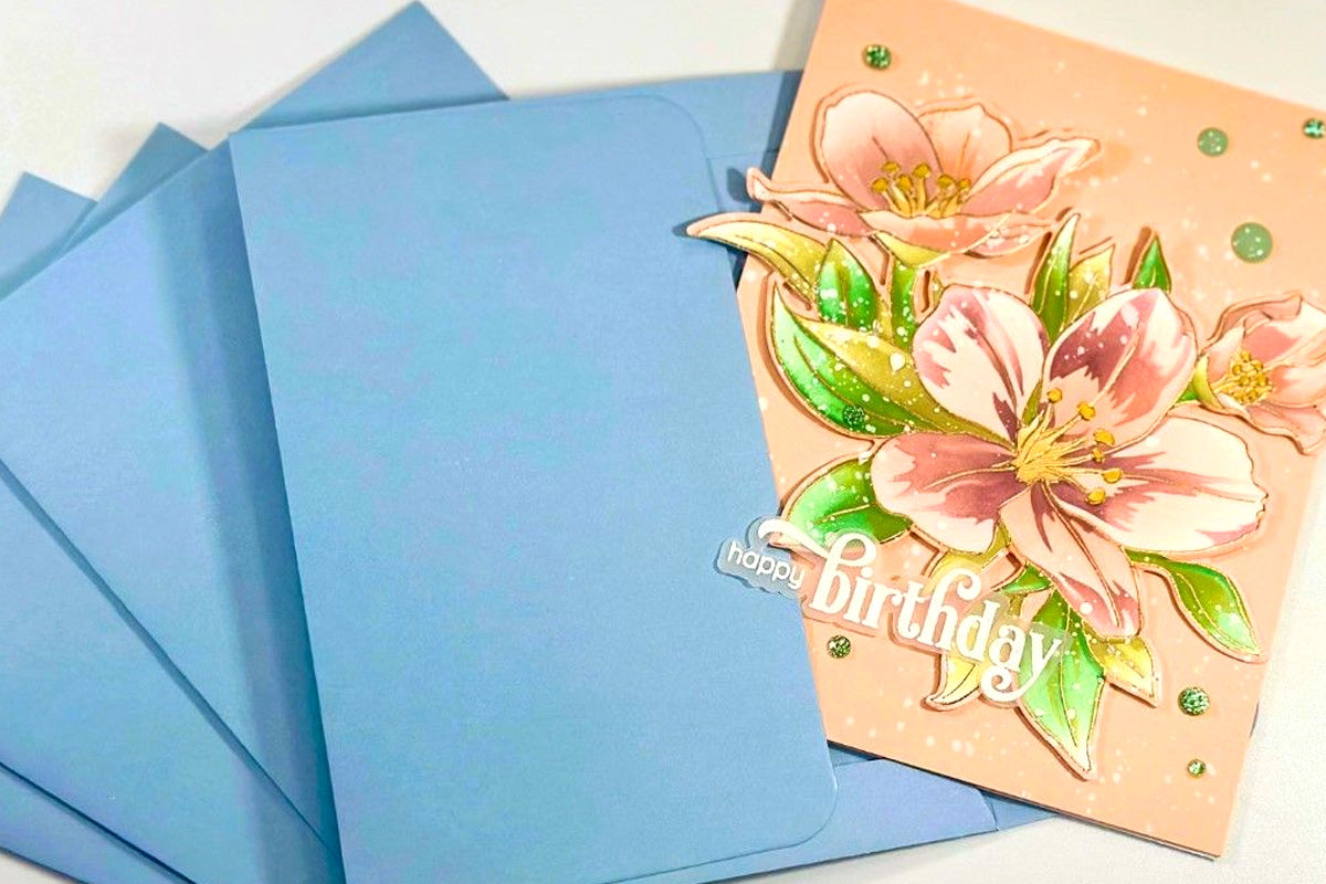 Peach and gold floral birthday card on top of a stack of Icy Water colored envelope for card making